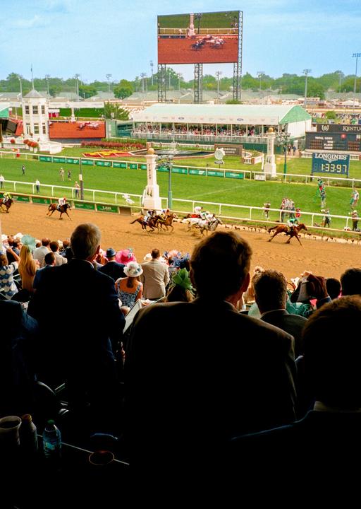 Spectators watch a horse race from a grandstand at Churchill Downs.