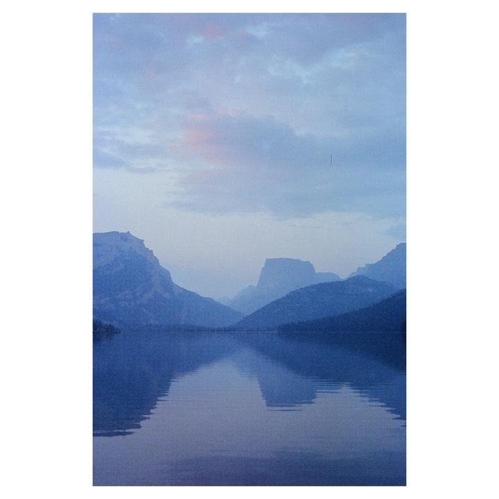 A calm lake reflects the mountains and sky at dusk.