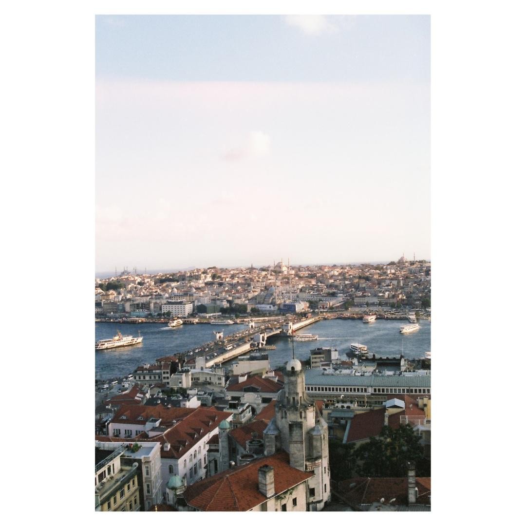 A city with many buildings and a bridge over a body of water is visible under a clear sky.