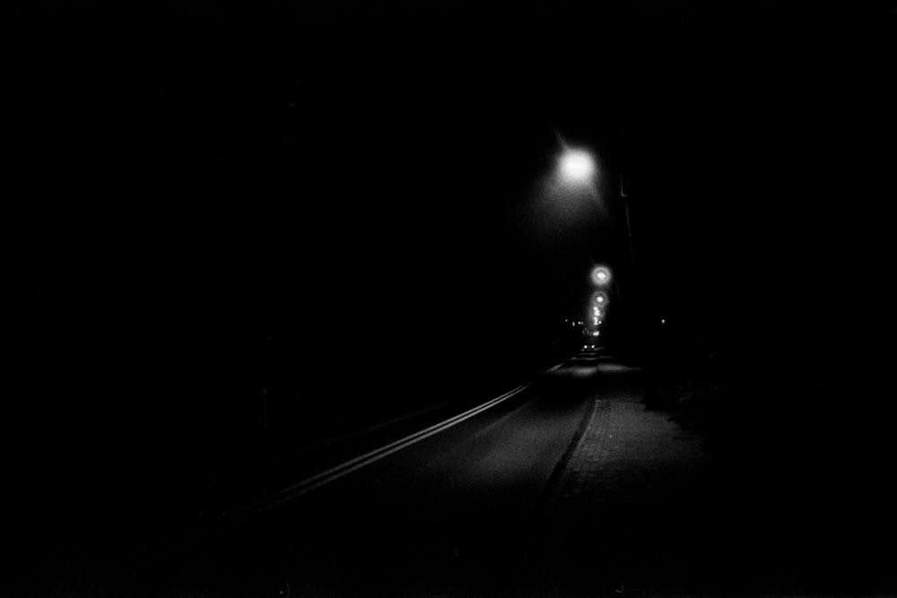 A dark road with streetlights stretching into the distance is visible at night.