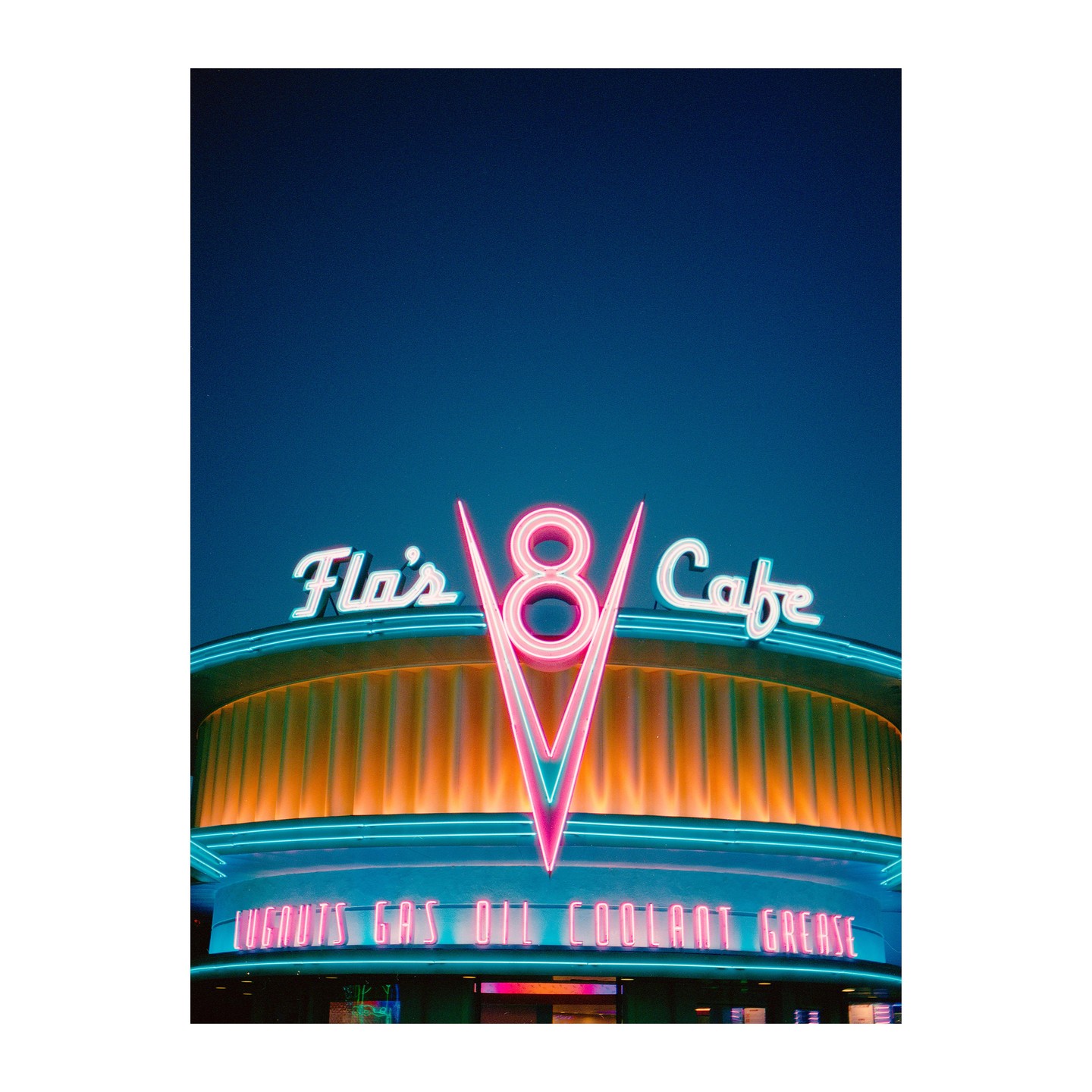 A neon sign for Flo's V8 Cafe is illuminated against a dark blue sky.