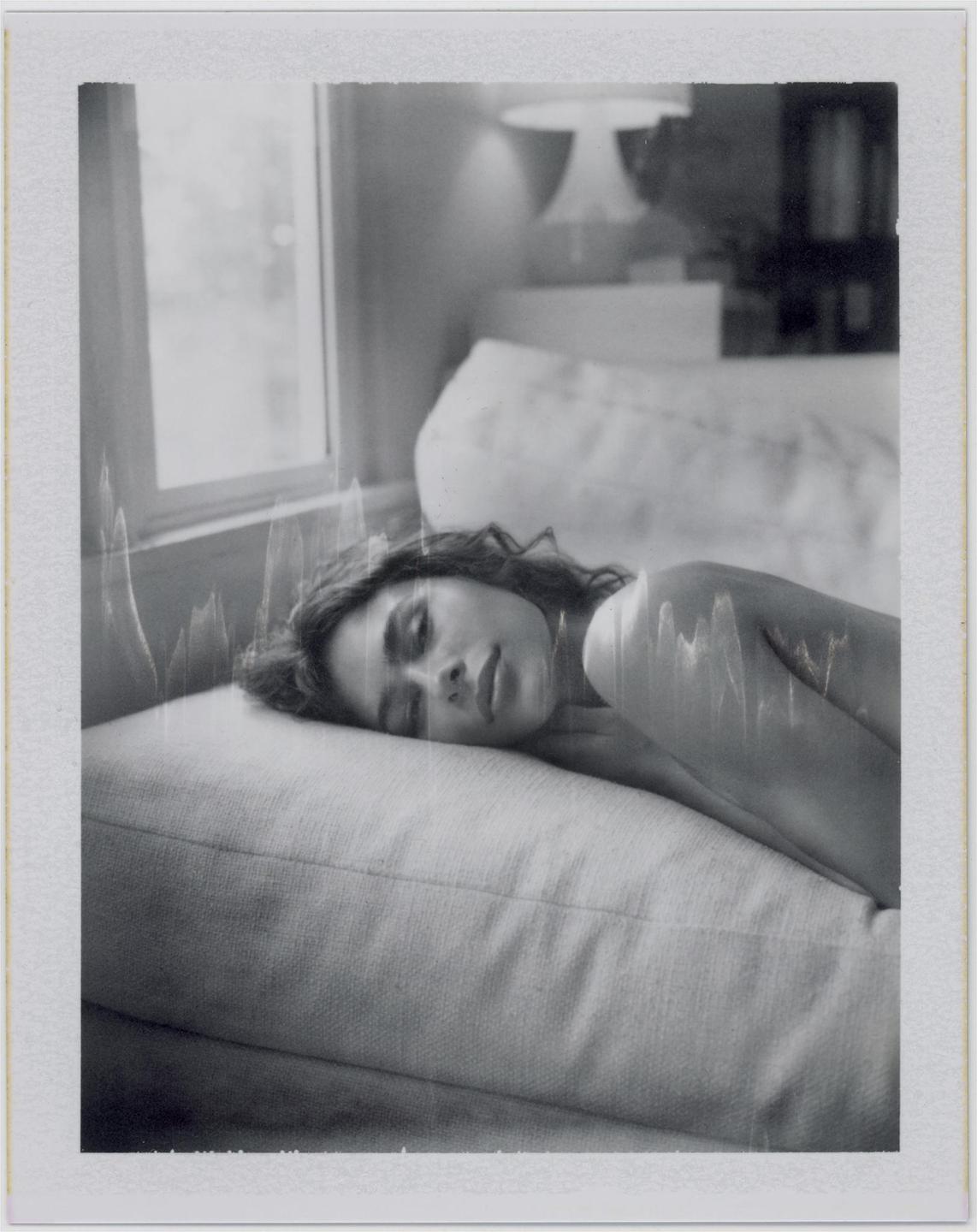 A woman with closed eyes rests her head on a pillow.