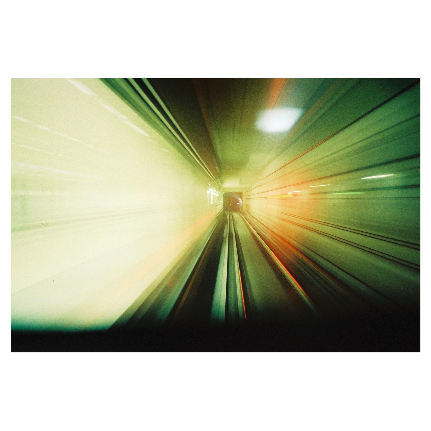 The view from the front of a subway shows the tracks and tunnel with motion blur.