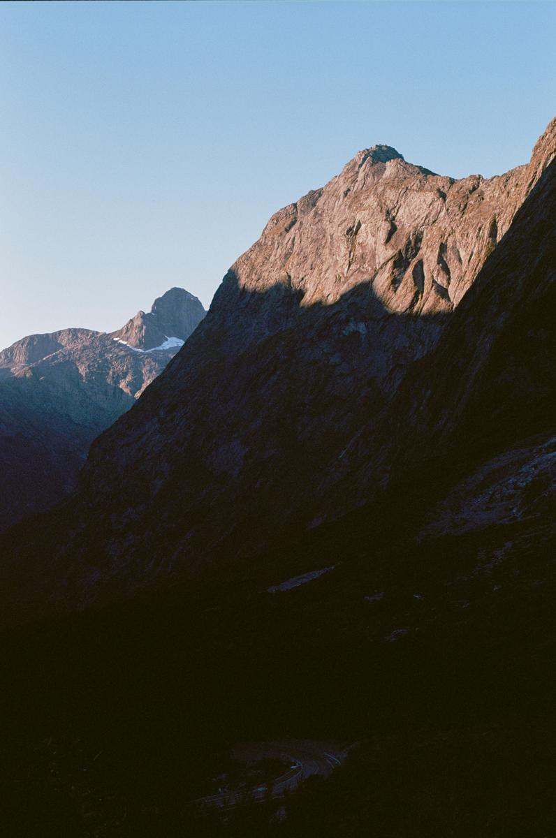 A mountain range is illuminated by the sun on one side and cast in shadow on the other.
