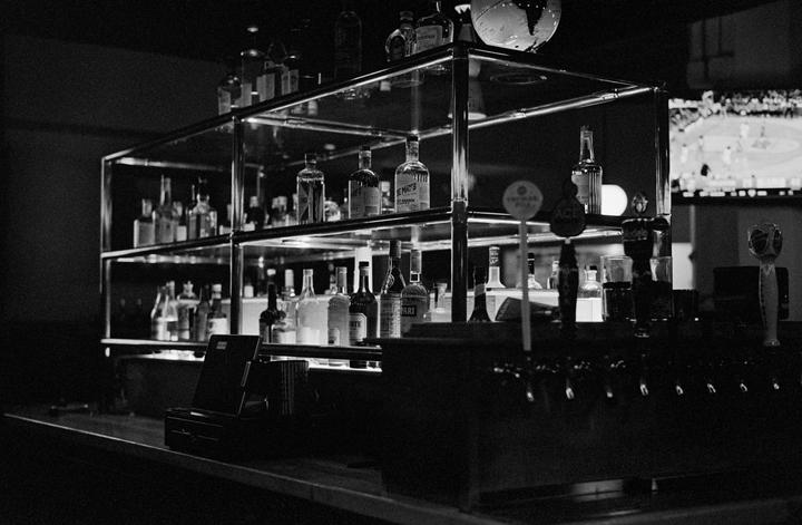 A bar counter is visible with shelves of liquor bottles and beer taps.