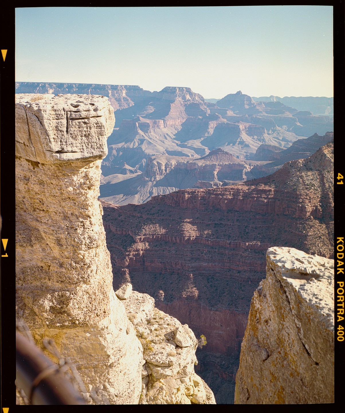 A vast canyon stretches into the distance, with a large rock formation in the foreground.