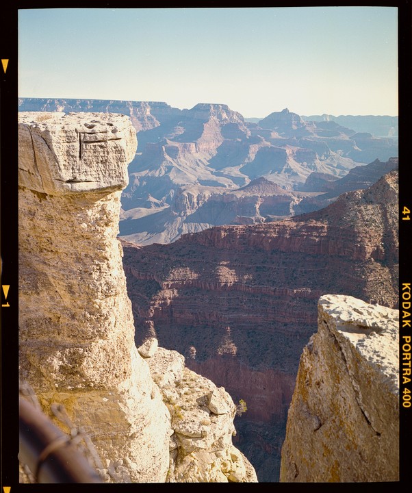 A vast canyon stretches into the distance, with a large rock formation in the foreground.