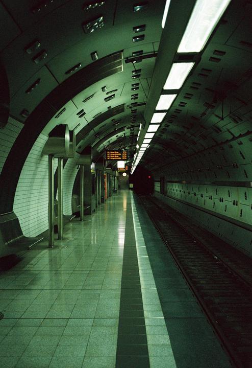 A long, empty subway platform stretches into the distance, illuminated by overhead lights.