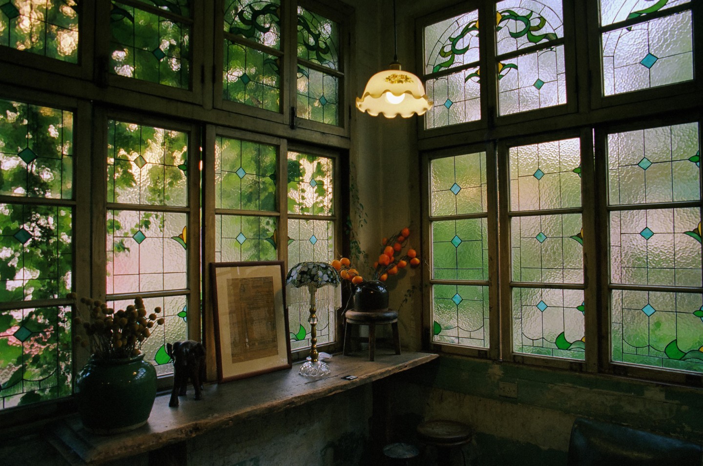 A cozy corner of a cafe features stained glass windows, a wooden counter, and various decorative items.
