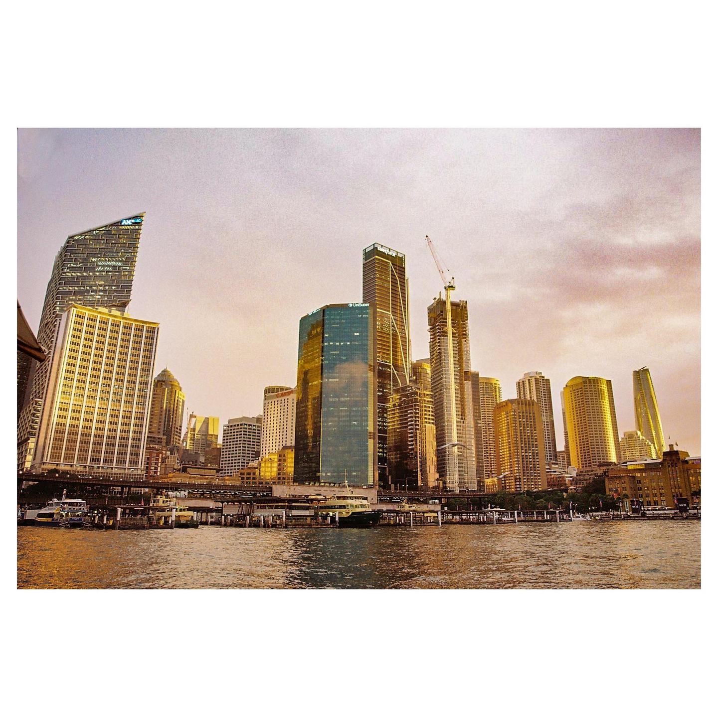 A cityscape with many tall buildings is visible across a body of water under a cloudy sky.