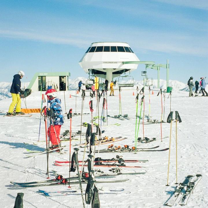 People are skiing and snowboarding on a snowy mountain with a ski lift in the background.