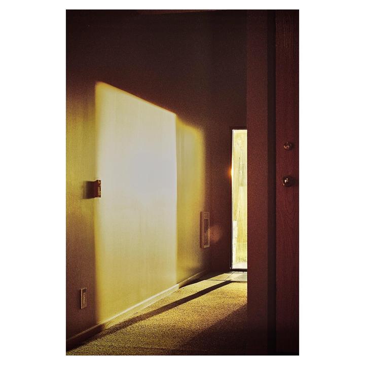 Sunlight streams into a hallway with a closed door on the right.