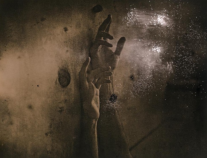 Two hands reach up towards a shower of sparkling particles.