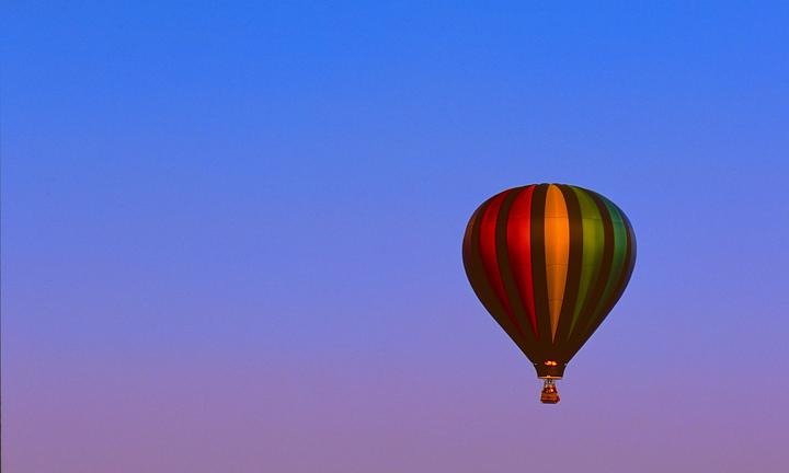 A colorful hot air balloon floats against a blue and purple sky.