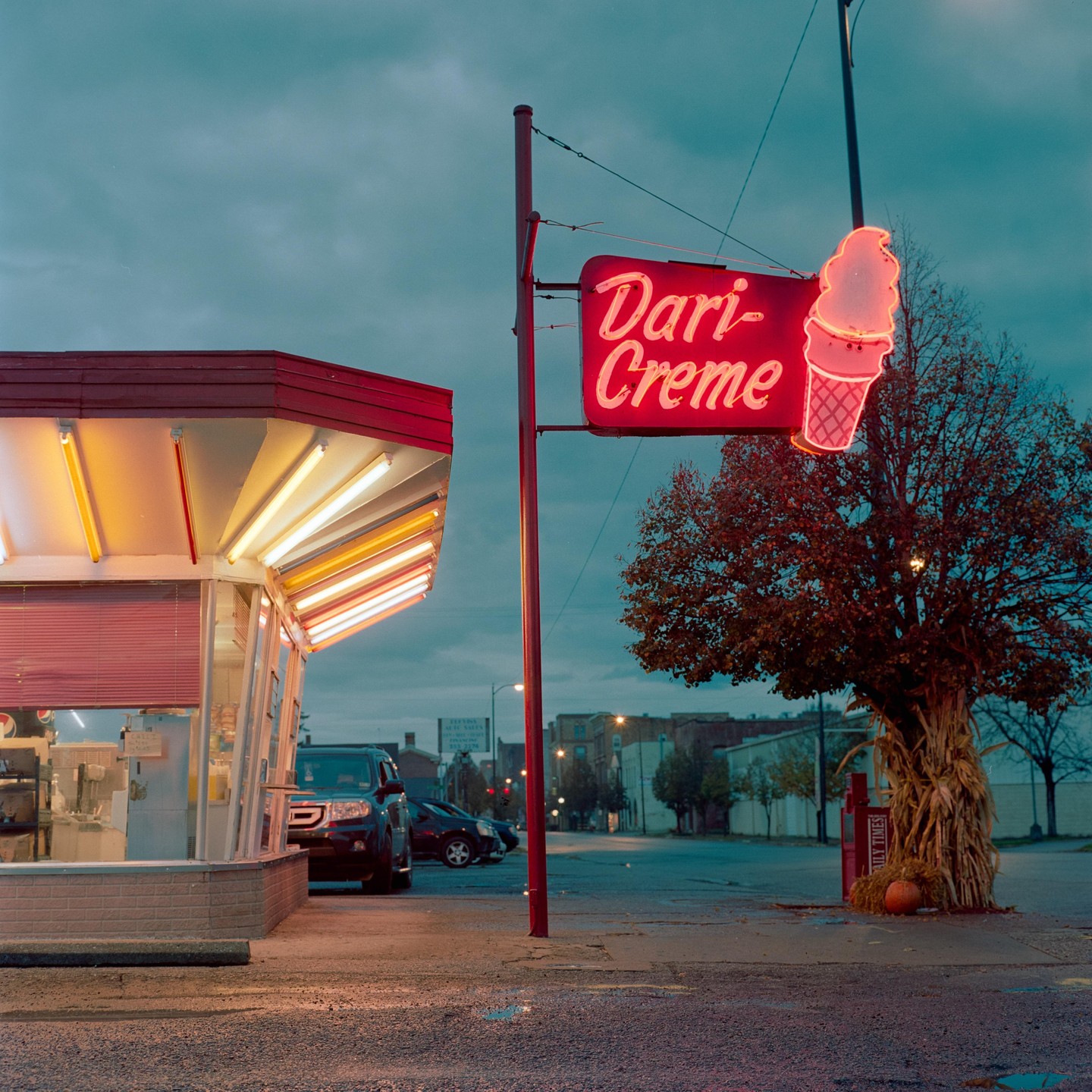 A Dari-Creme ice cream stand with a neon sign is illuminated at dusk.