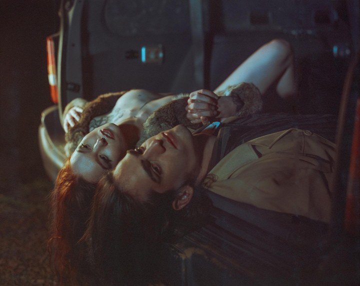 A couple is lying in the trunk of a car at night.