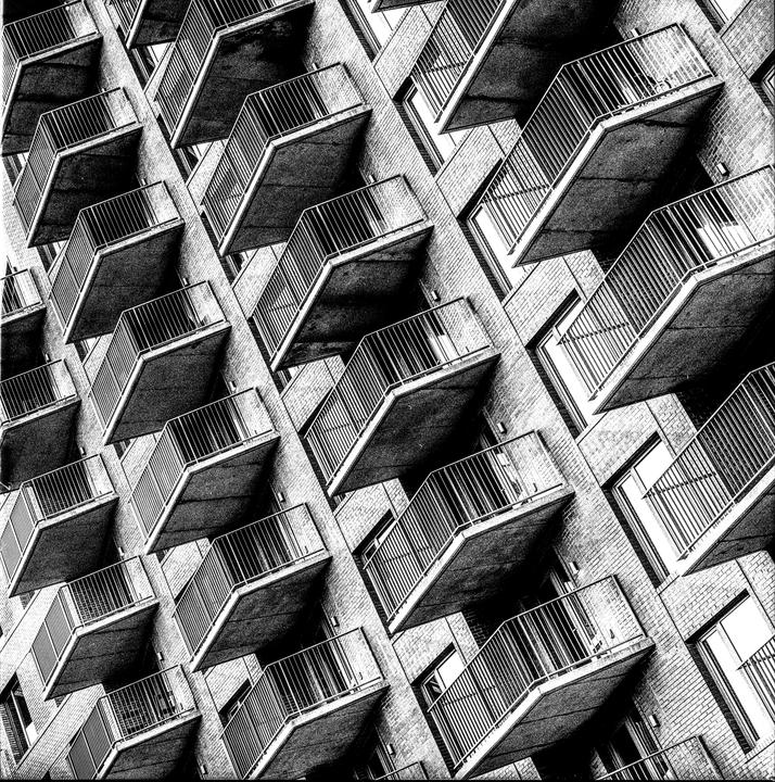 A black and white photograph shows a repeating pattern of balconies on a building.