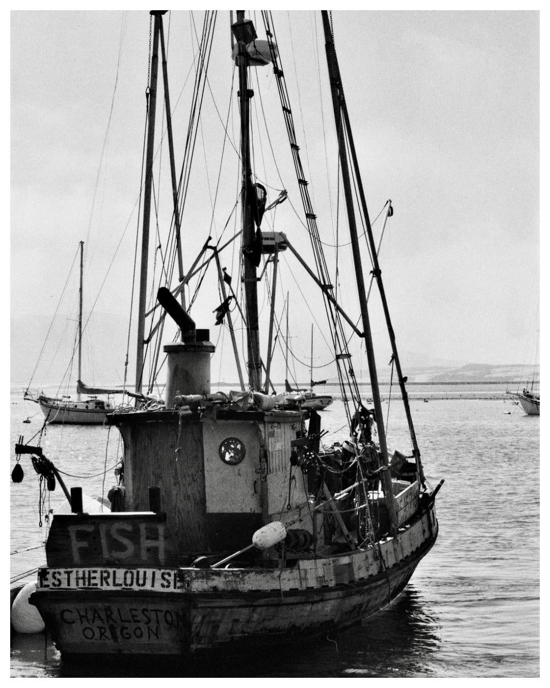 A fishing boat named Estherlouise from Charleston, Oregon, is docked in the water with other boats in the background.