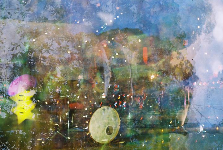 A multiple exposure shows a drum, a christmas tree, and a forest reflected in a lake.