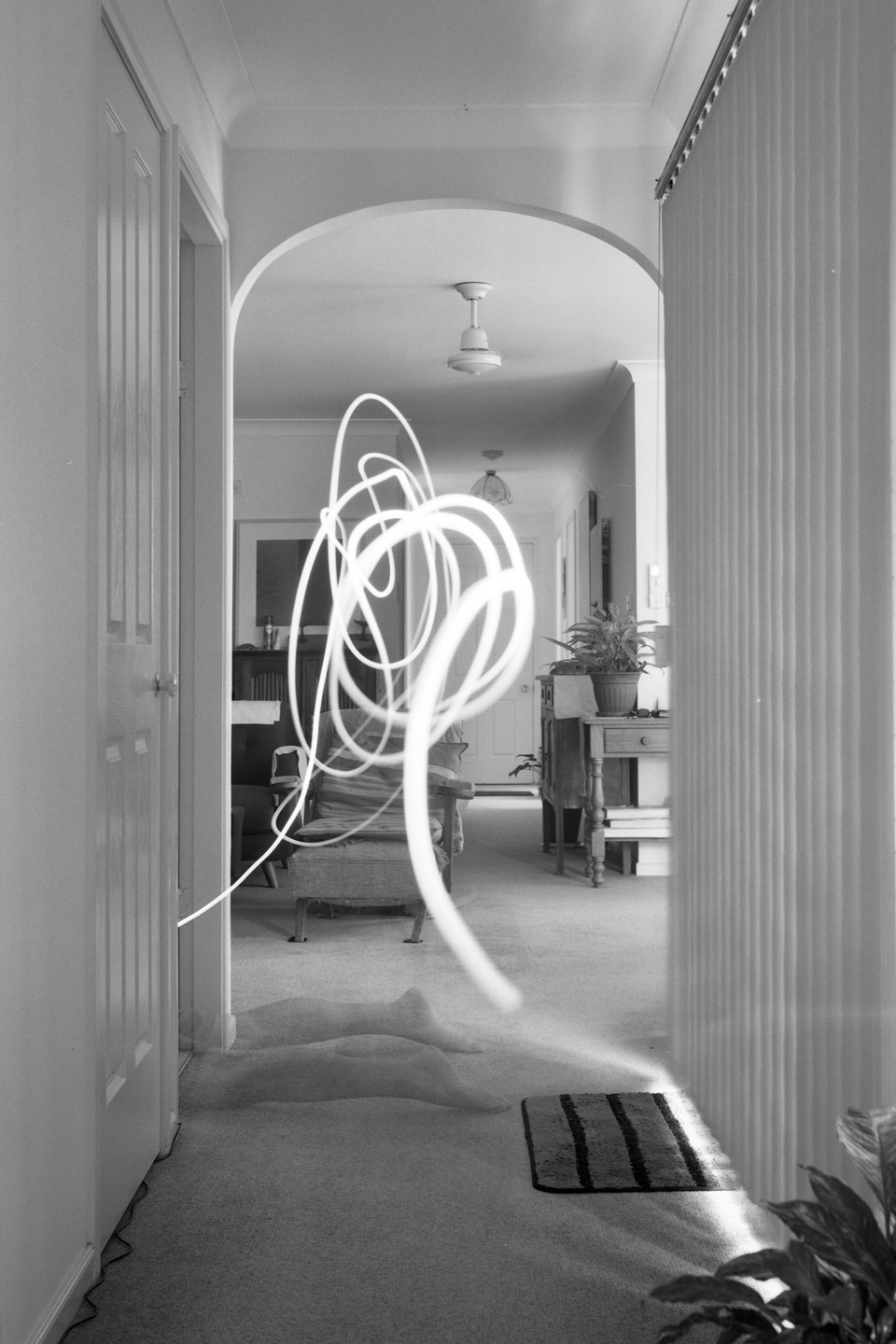 A long exposure photograph shows a light trail and the ghostly legs of a person in a hallway.