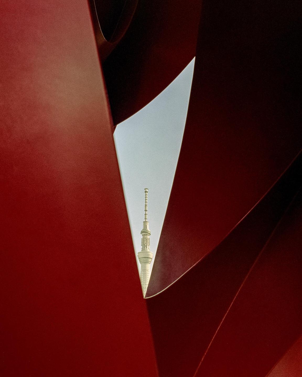 A tall white tower is visible through a triangular opening in a red structure.