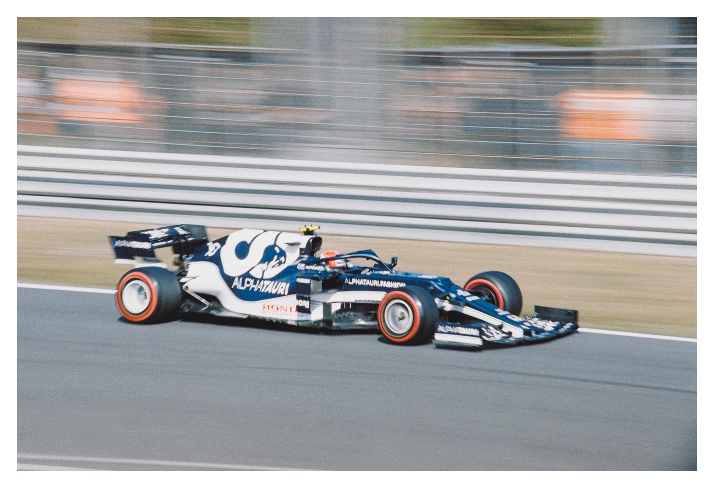 A blue and white race car speeds along a track with a blurred background.