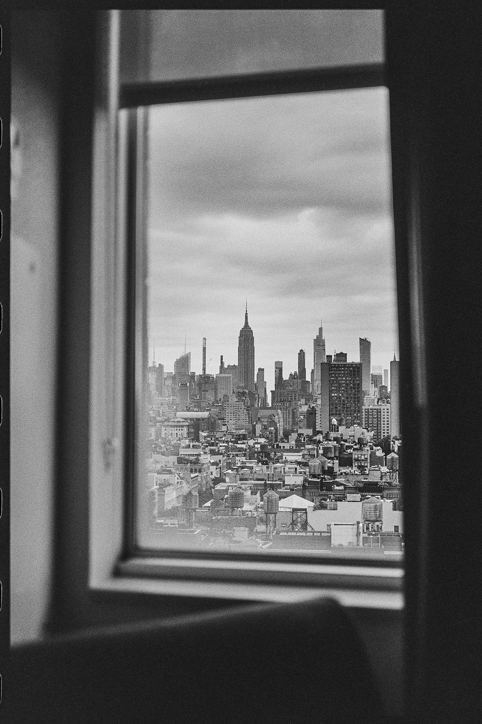 A cityscape with many buildings and water towers is visible through a window.