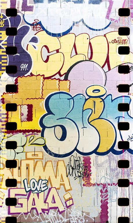 A wall covered in colorful graffiti is framed by the sprockets of a film strip.