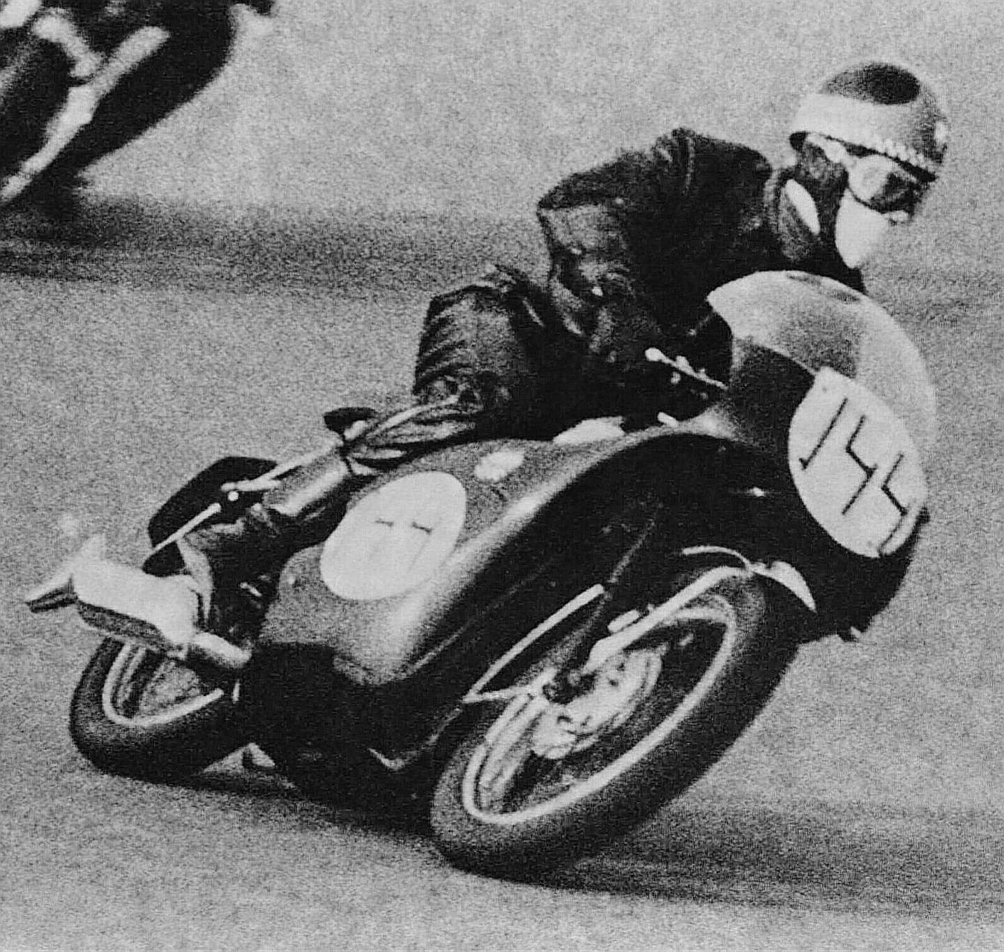 A man on a motorcycle leans into a turn on a race track.