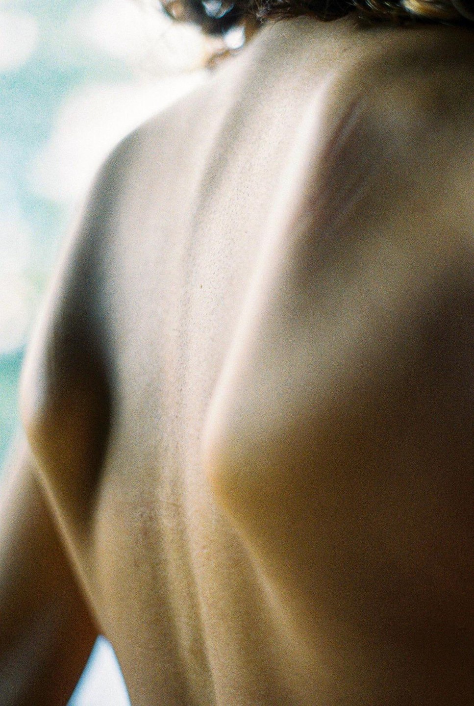 The back and shoulder of a person are visible with light creating shadows and highlights.