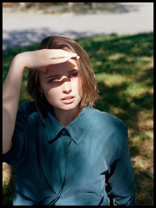A woman shields her eyes from the sun with her hand.