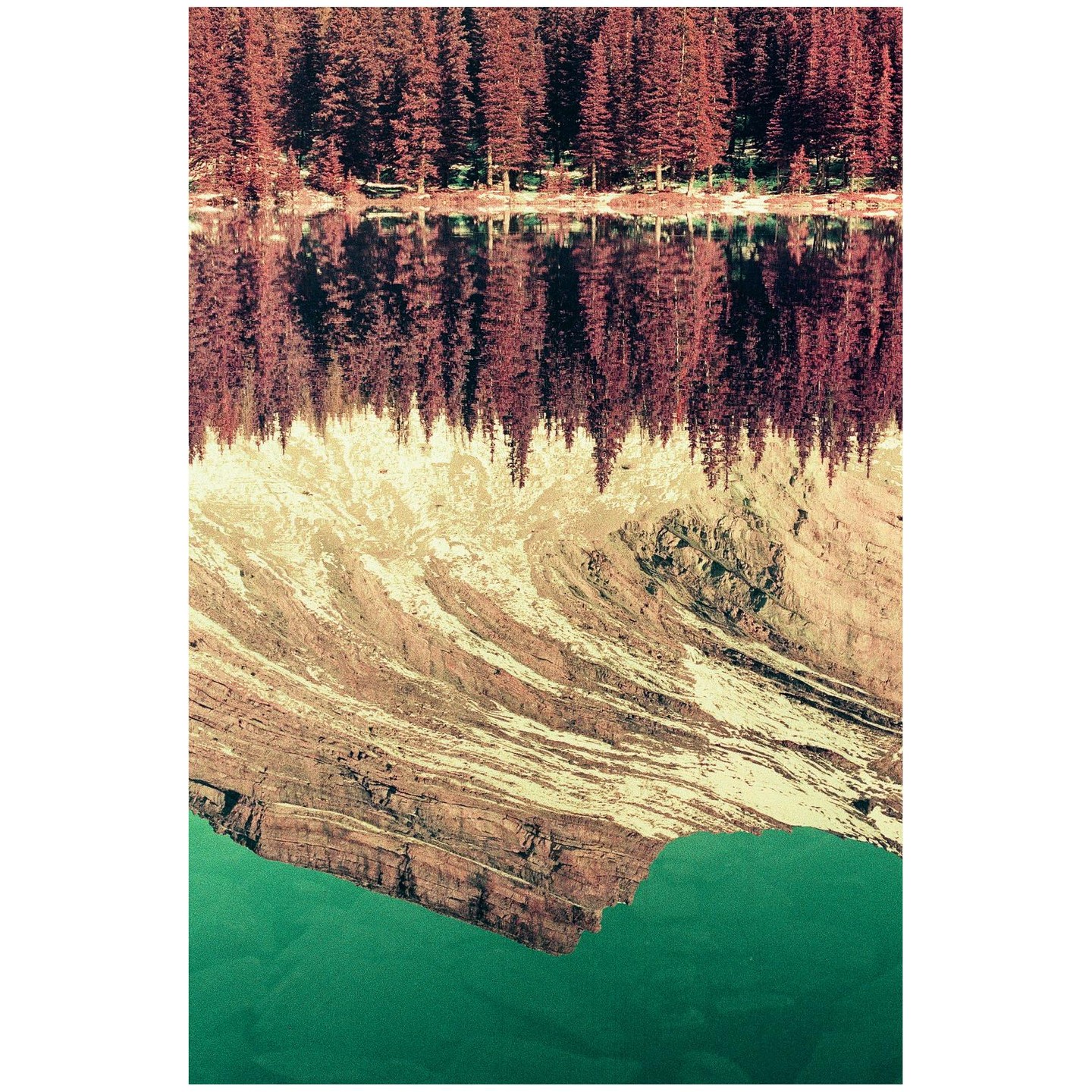 A mountain with snow and a forest are reflected in a lake.