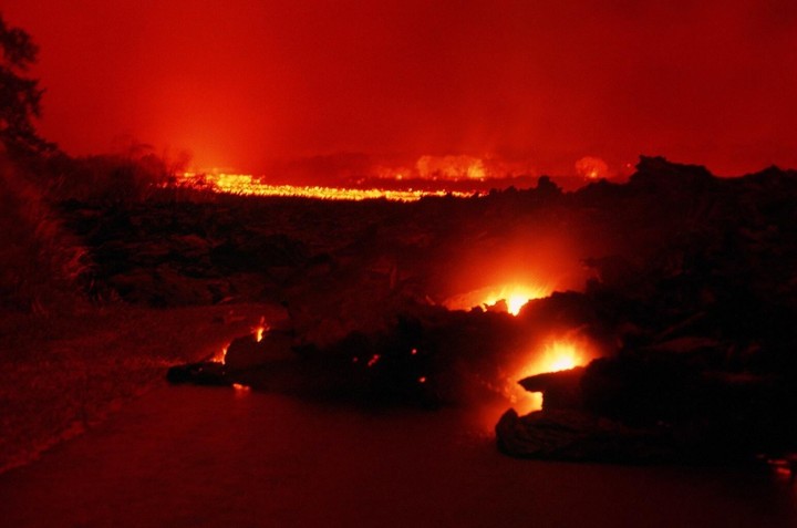 Molten lava flows into the ocean under a red sky during the Kilauea eruption.