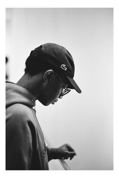 A man wearing a baseball cap and glasses looks down, holding onto a railing.