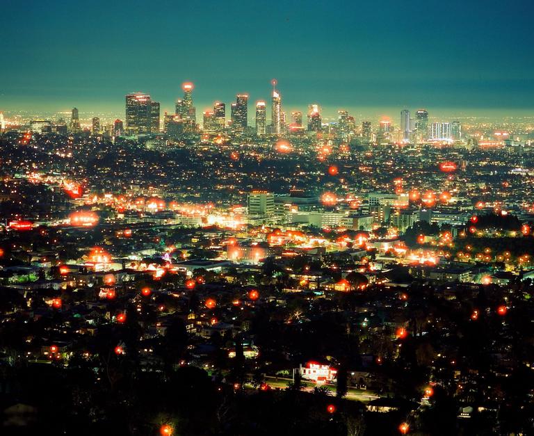 A panoramic view of the Los Angeles skyline at night, with city lights stretching into the distance.