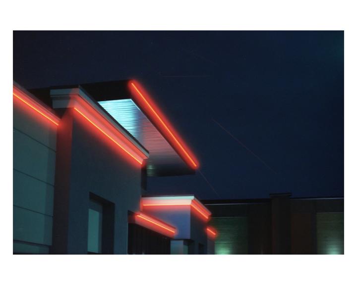 Red neon lights illuminate the edges of a building against a dark night sky.