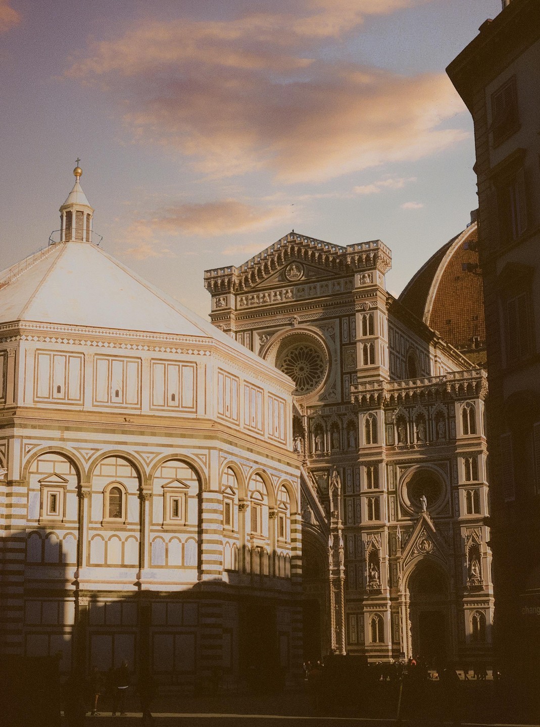 The Florence Cathedral and Baptistery are illuminated by the warm light of dusk.
