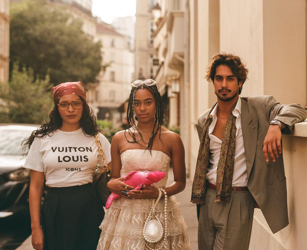 Three people pose for a group portrait on a city street.