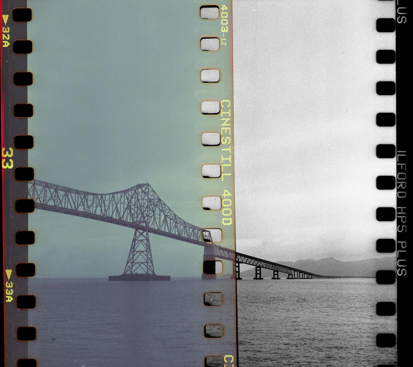 A bridge spans across a body of water, with a mountain range visible in the distance.