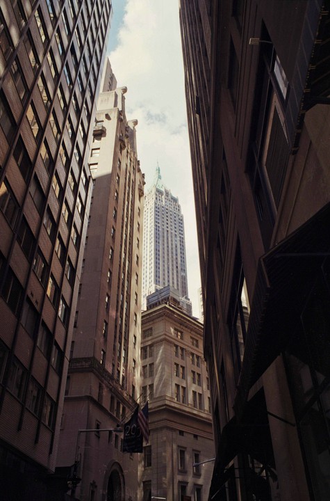 Looking up at tall buildings in a city with a flag hanging from one building.