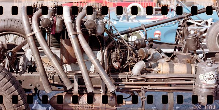 A close-up shot shows the engine and exhaust pipes of a vintage race car.