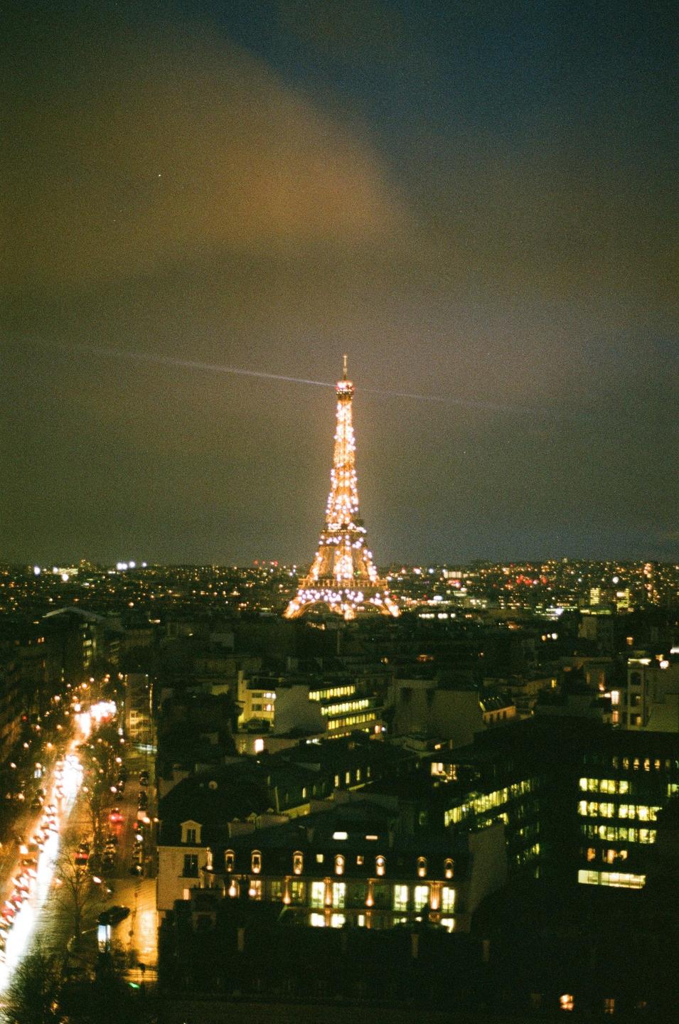 The Eiffel Tower is illuminated at night, overlooking the city of Paris.