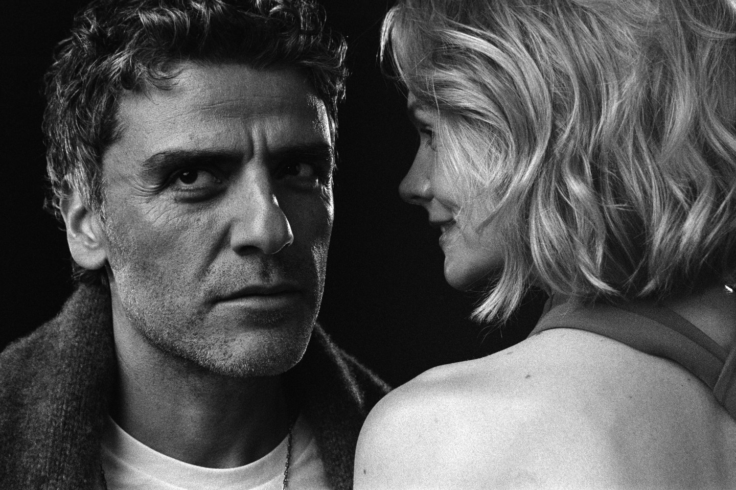 A man looks directly at the viewer while a woman looks at him from the side.