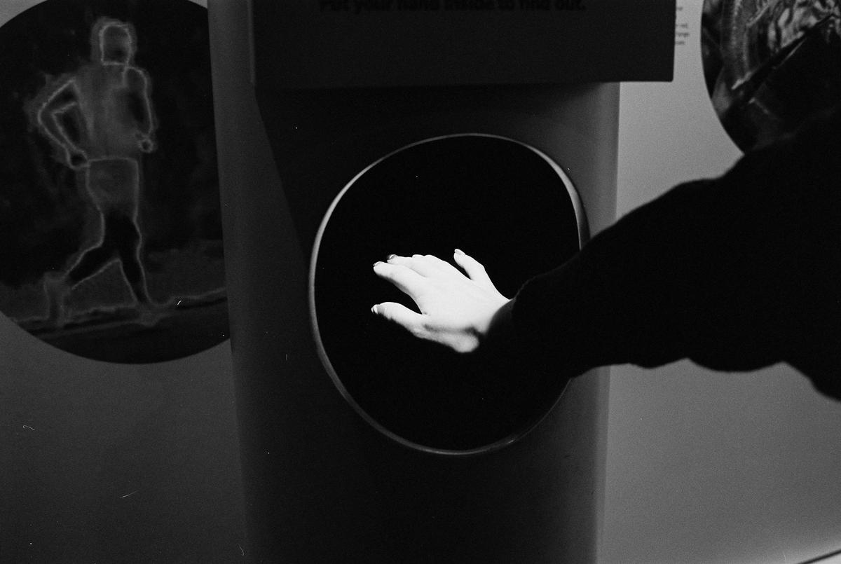 A hand reaches into a dark circular opening on a display with a glowing outline of a runner in the background.
