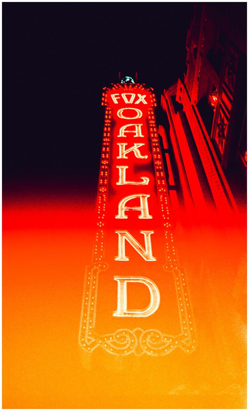A neon sign for "Fox Oakland" glows red and orange against a dark night sky.