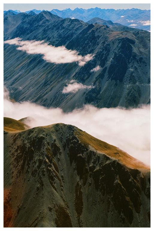 Clouds fill a valley between two mountain ranges.