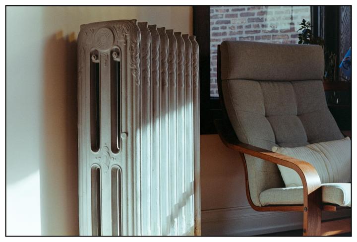 Sunlight illuminates a radiator and a chair in a room.