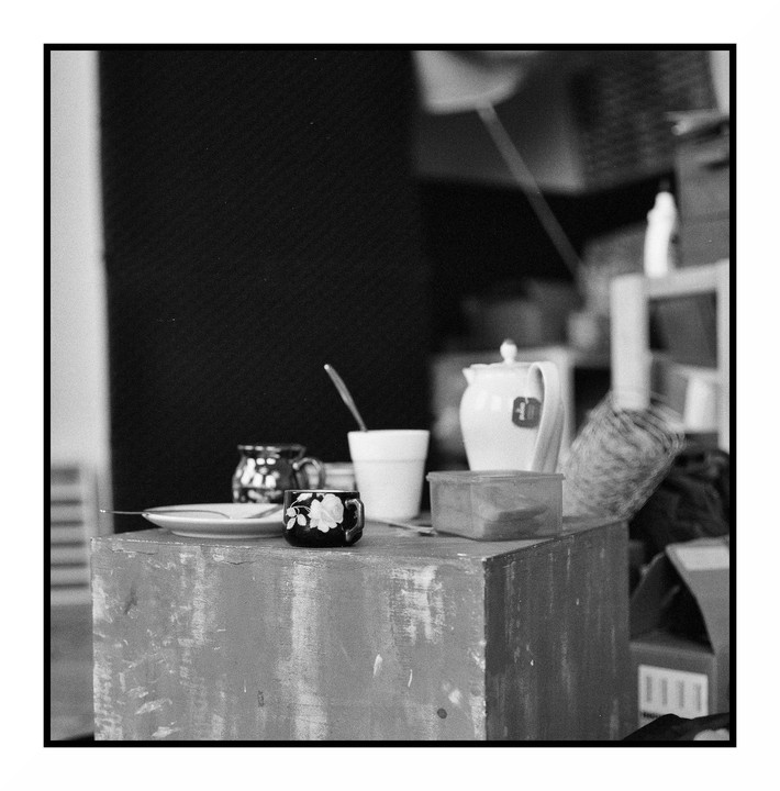 A small table holds a teapot, cups, and a small plate.