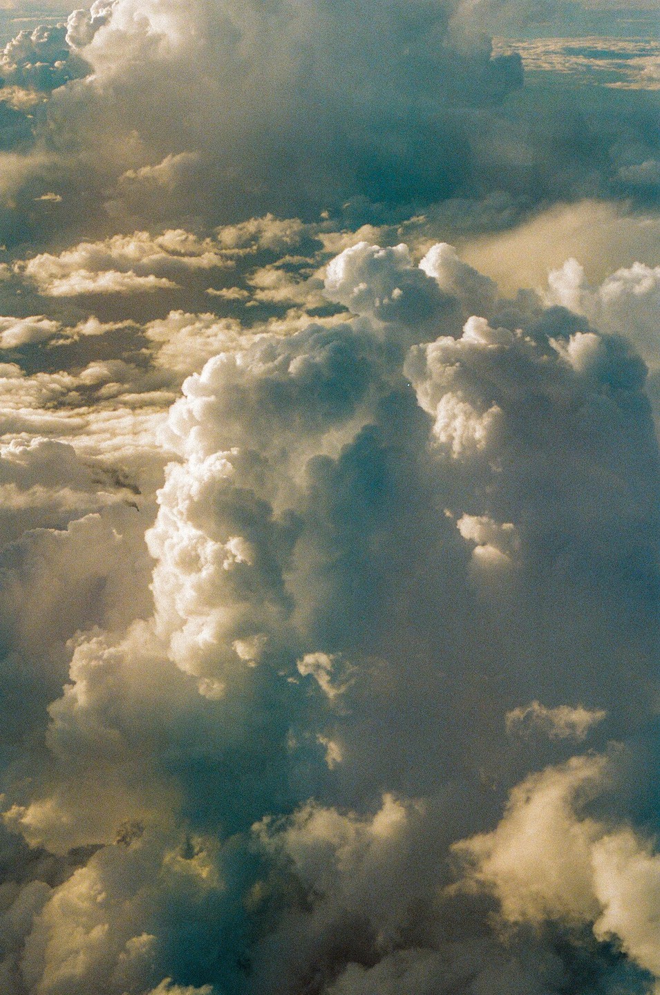 A dramatic sky is filled with large, fluffy clouds, some illuminated by sunlight and others in shadow.