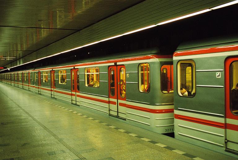 A subway train with red doors and a grey body is stopped at a station platform.